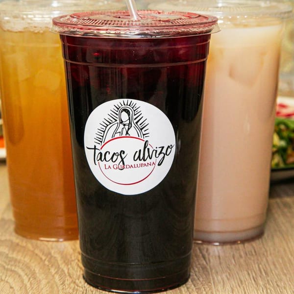 Three aguas frescas, including a dark red jamaica, an orange, and a light brown horchata.